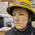 Iconic 1970s Firemans Uniform With Yellow Yellow Waterproof Overtrousers And Yellow Cork Helmet With Blue Nomex Fire Tunic mannequin-man performming as a Museum Dummy: Mannequin wearing a 1976 Nomex jacket, yellow cork helmet and classic yellow PVC leggings. for Essex Fire Museum on 26/11/2023