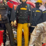 Iconic 1970s Firemans Uniform With Yellow Yellow Waterproof Overtrousers And Yellow Cork Helmet With Blue Nomex Fire Tunic mannequin-man performming as a Museum Dummy: Mannequin wearing a 1976 Nomex jacket, yellow cork helmet and classic yellow PVC leggings. for Essex Fire Museum on 26/11/2023